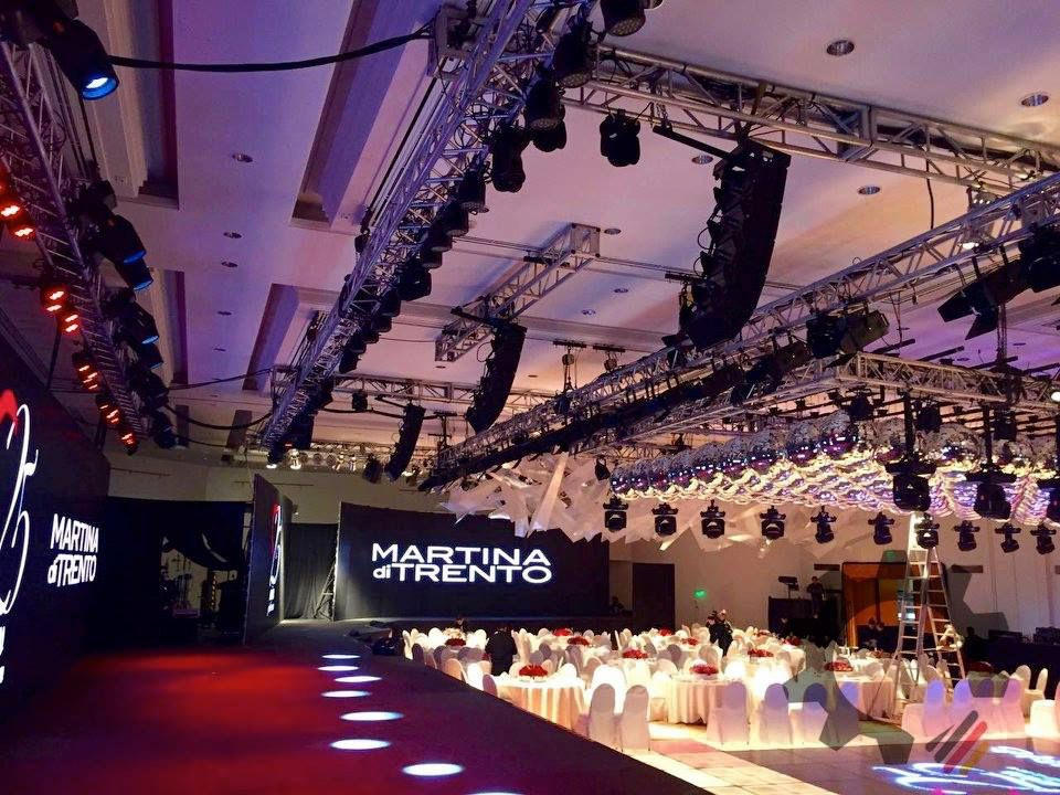 Estructura de trusses con iluminación y pantallas LED sobre mesas de gala en salón de eventos — rigging Stöessel
