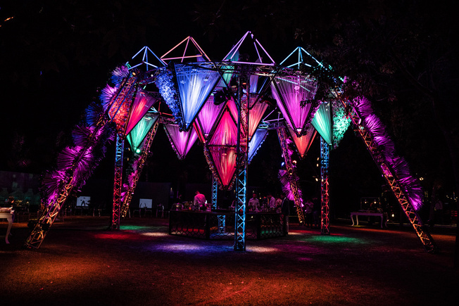 Estructura geométrica de trusses con conos iluminados en colores en evento al aire libre de noche — Stöessel