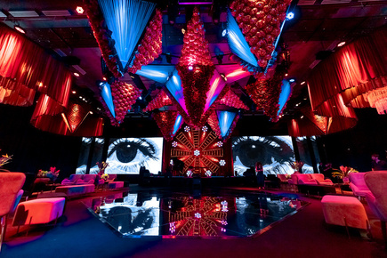 Ambientación inmersiva con esculturas suspendidas, pantallas LED y piso espejado en evento — producción técnica Stöessel